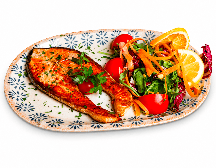 Salmone alla griglia con insalata mista, pomodorini, carote e limone, servito su piatto decorato